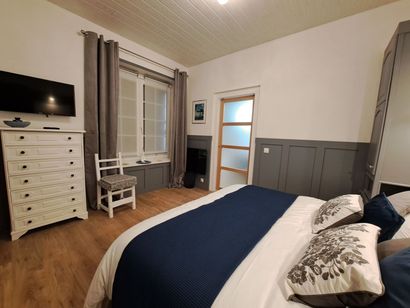 bedroom with king sized bed, white and blue bed linen and grey semi panelled walls