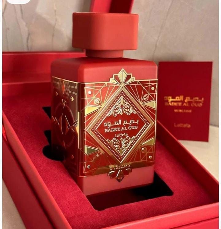 Frasco de perfume rojo en caja roja, letras doradas, texto árabe.