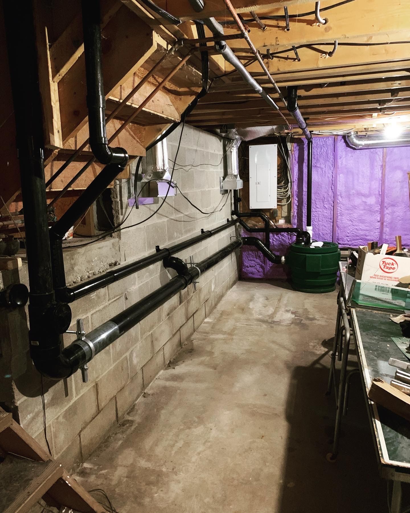A basement with a lot of pipes and a table.