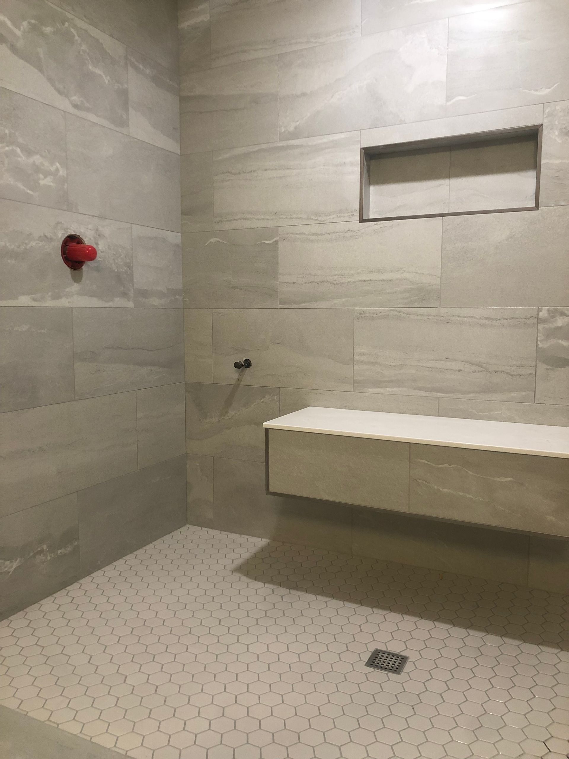 A shower with a bench and a shower head.