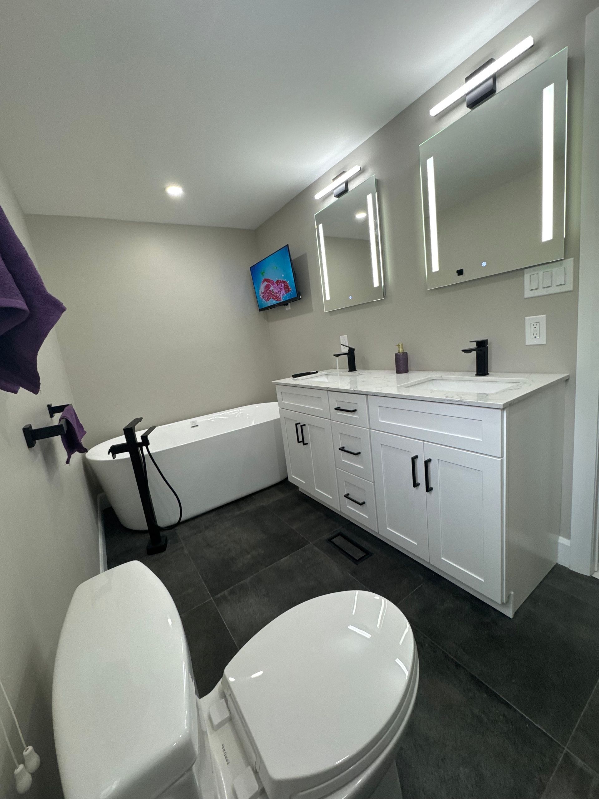 A bathroom with a toilet , sink , tub and mirrors.