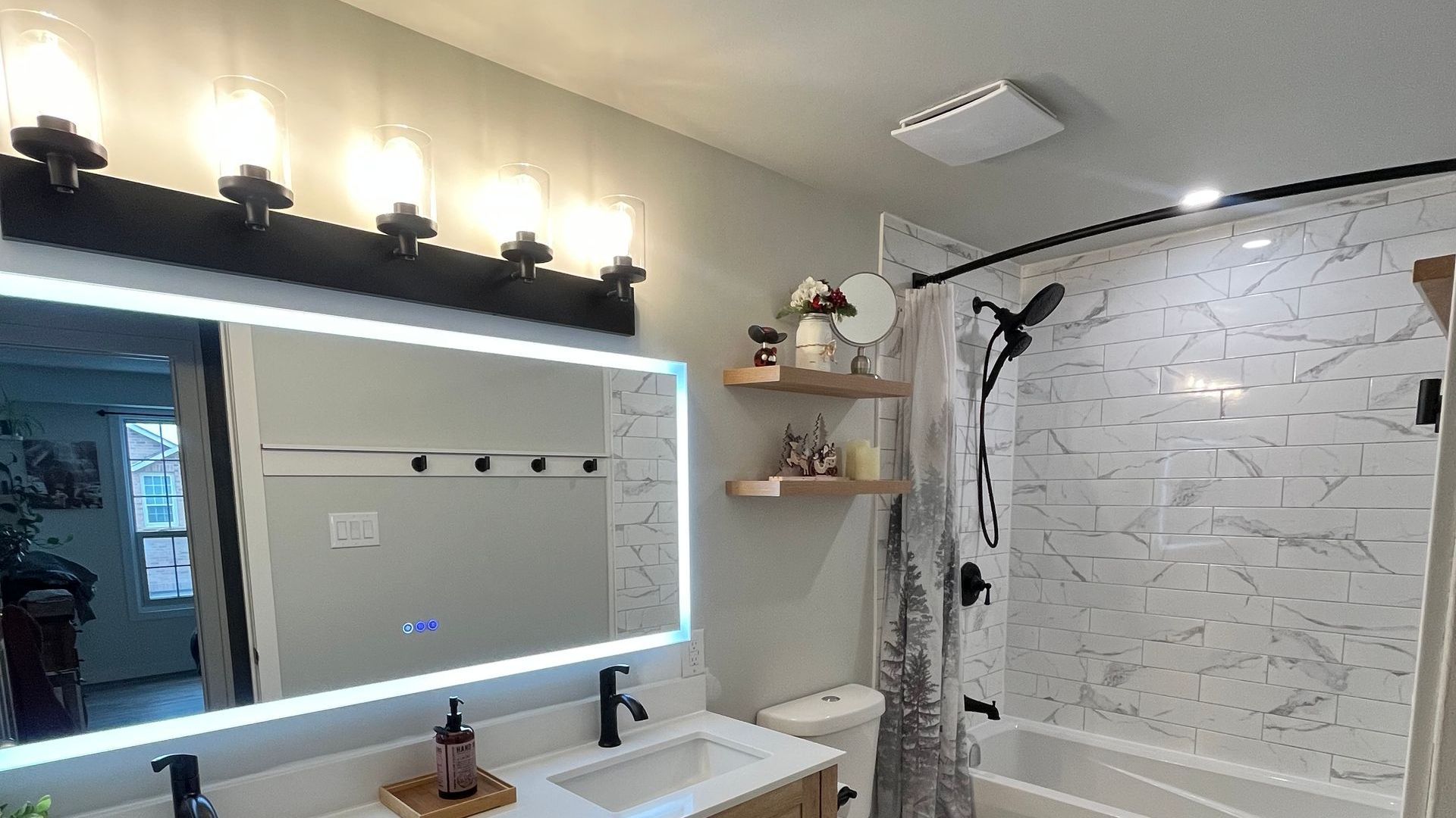 A bathroom with a sink , toilet , shower and mirror.