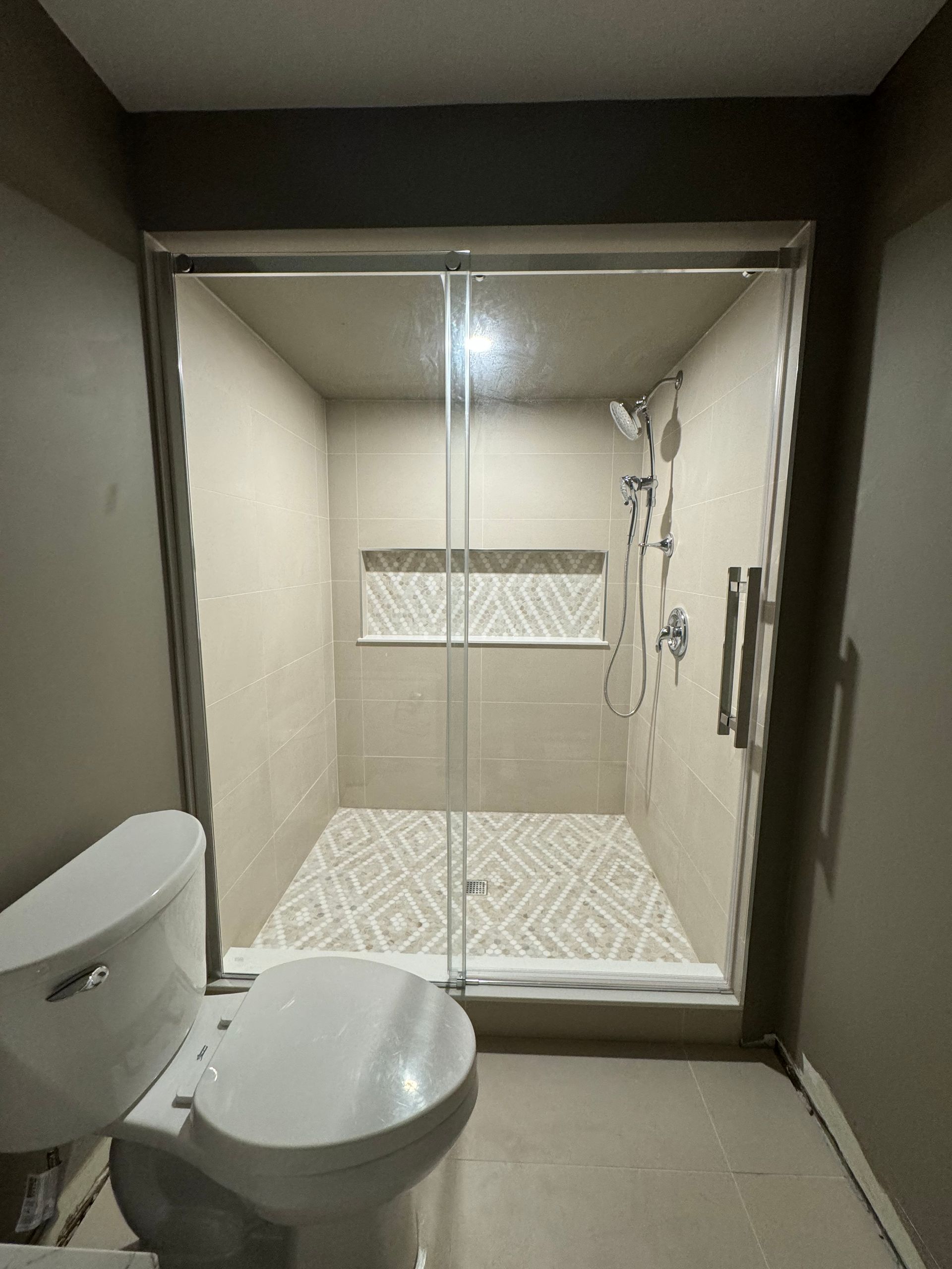 A bathroom with a toilet and a shower with a sliding glass door.
