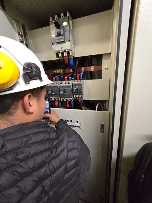 Una hilera de cajas de control eléctrico montadas sobre una estructura metálica, con un cableado organizado y colorido que recorre un almacén.