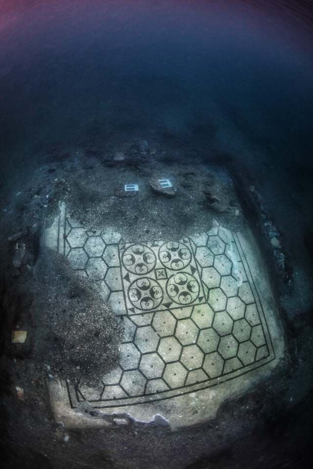 Underwater view of ancient mosaic floor with hexagonal and circular patterns.