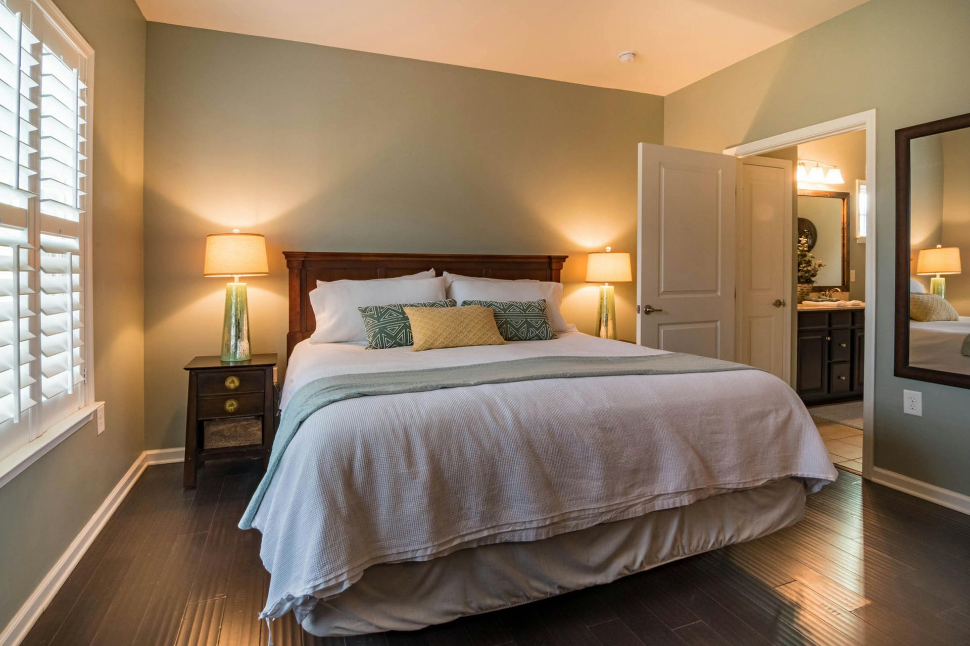 A bedroom with a bed , chair , rug and curtains.