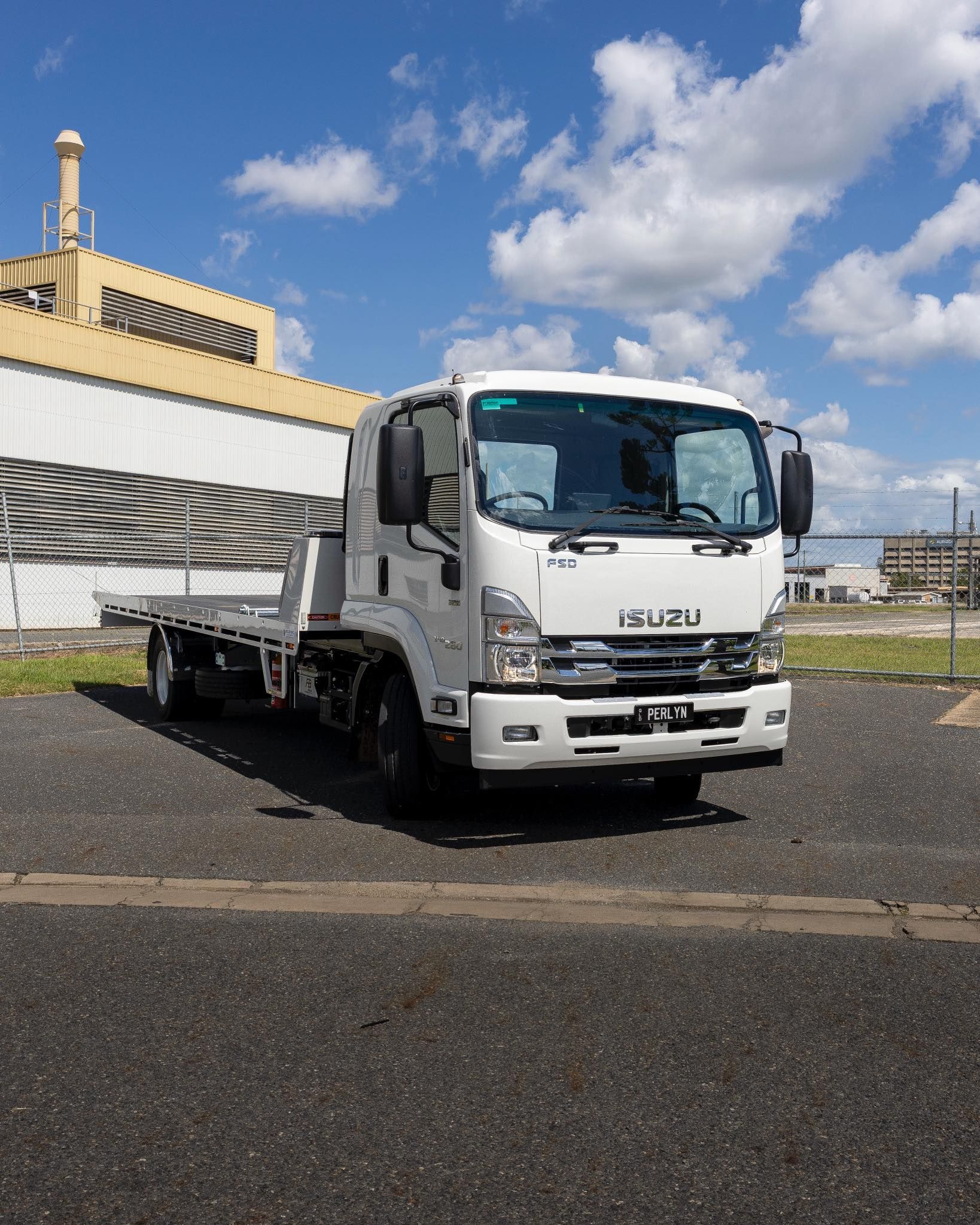 White flatbed truck parked in front of a building on a sunny day.— Perlyn Towing  in Rockhampton City, QLD