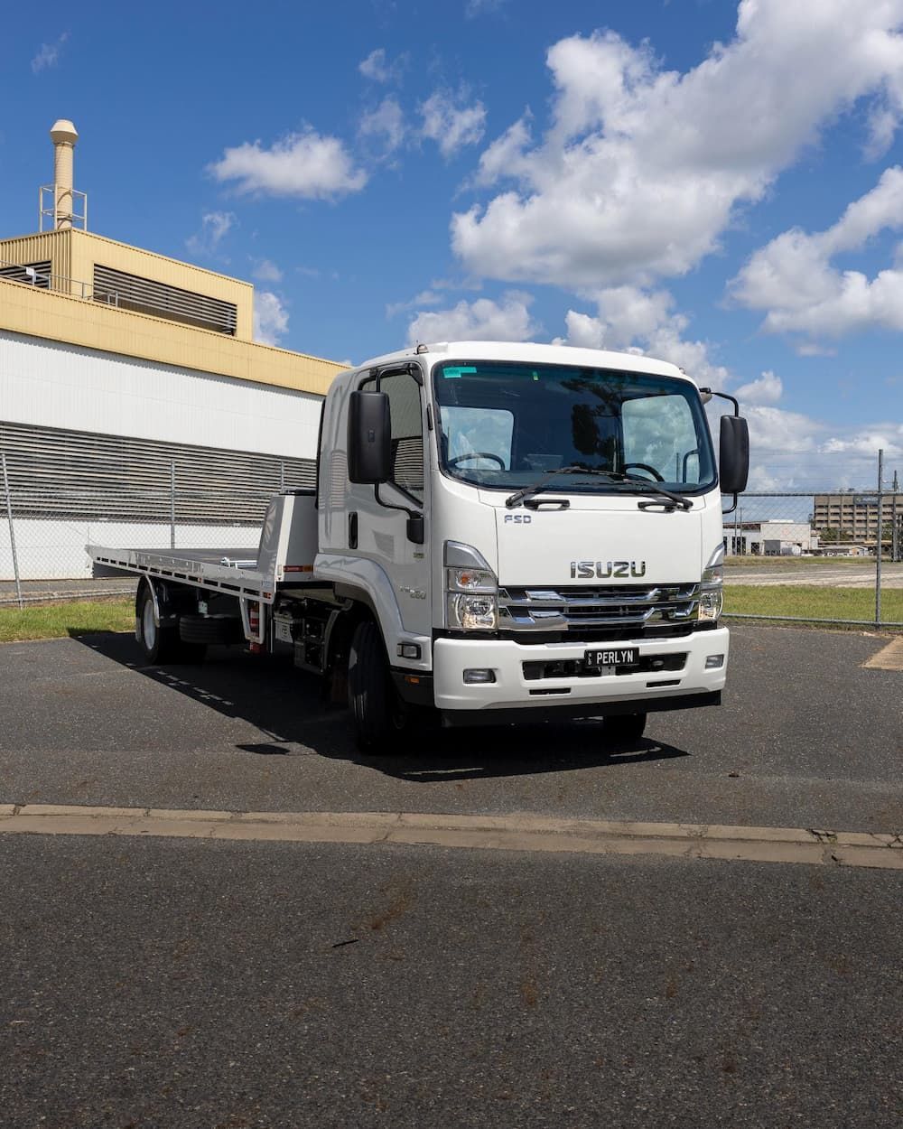 A White Isuzu Flatbed Truck is Parked on the Side of the Road — Perlyn Towing  in Rockhampton City, QLD