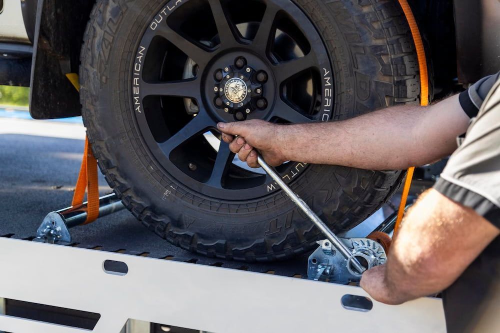 A Man is Changing a Tire on a Truck With a Wrench — Perlyn Towing  in Rockhampton City, QLD