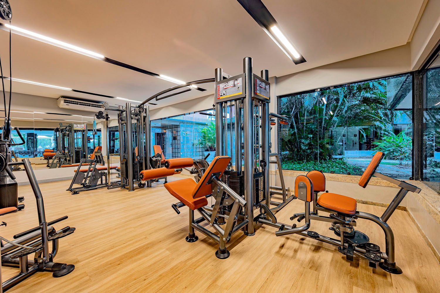 Uma academia cheia de equipamentos de ginástica e piso de madeira.
