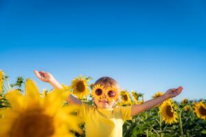 Um menino usando óculos de sol de girassol está parado em um campo de girassóis.