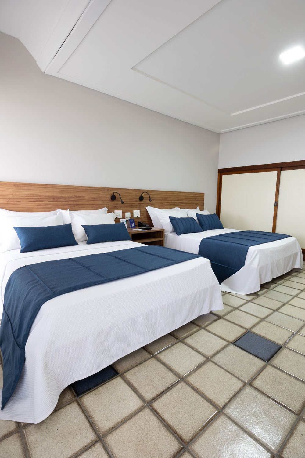 Um quarto de hotel com duas camas e piso de ladrilho.