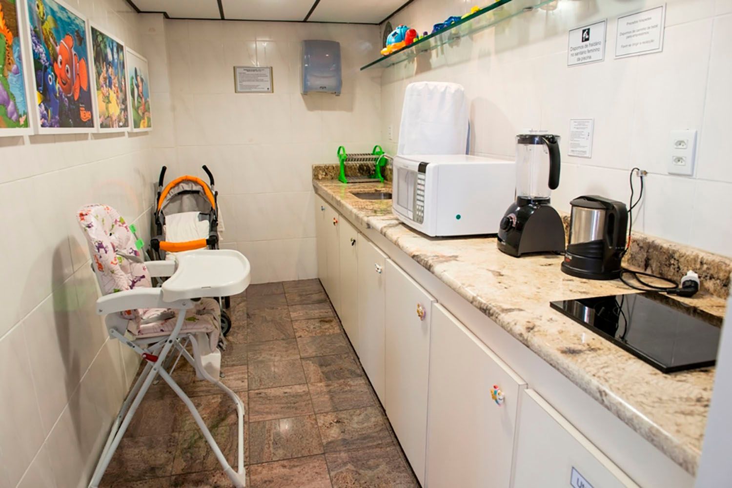 Uma cozinha com um carrinho de bebê e uma cadeira alta.