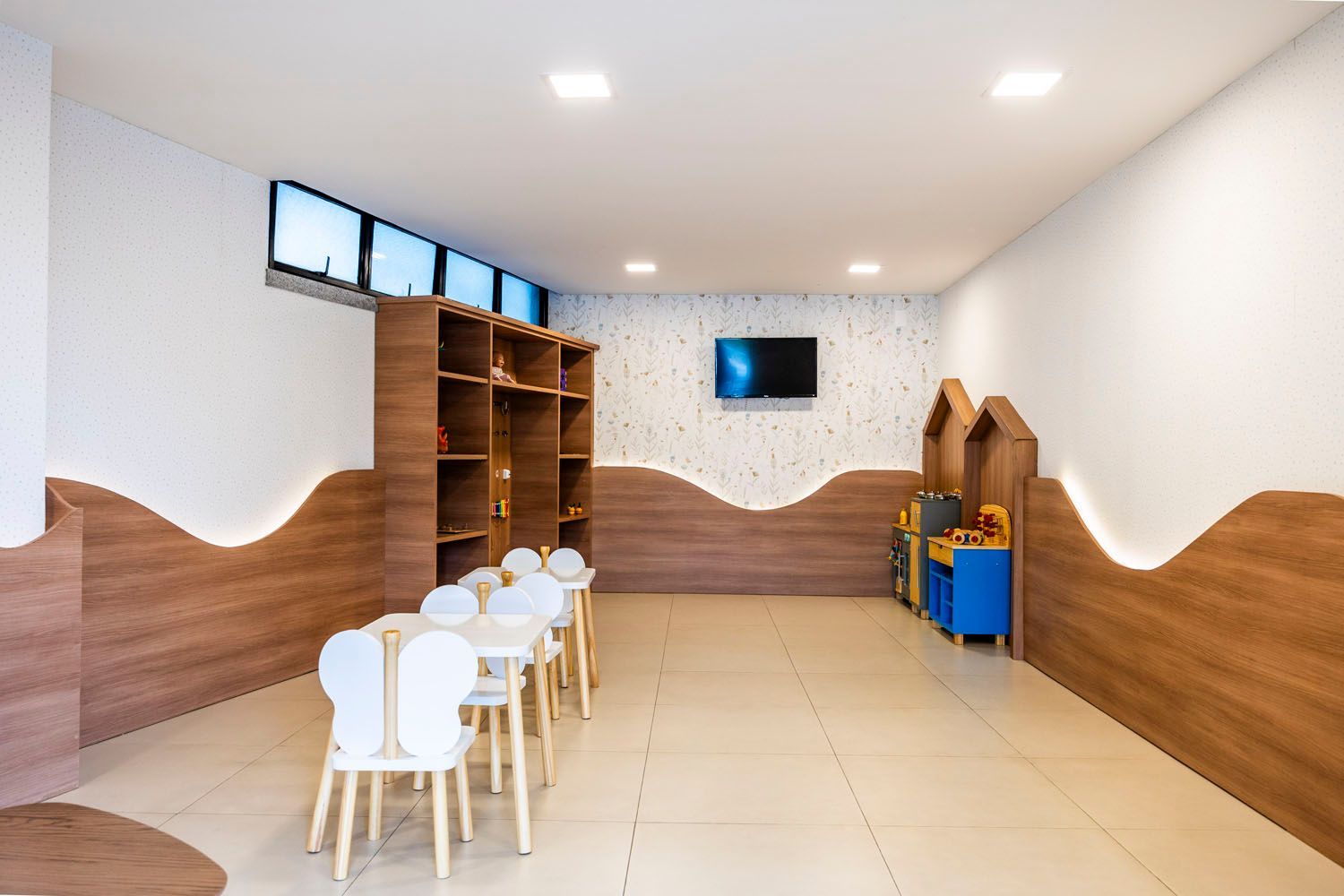 Uma sala com mesas e cadeiras e uma televisão na parede.