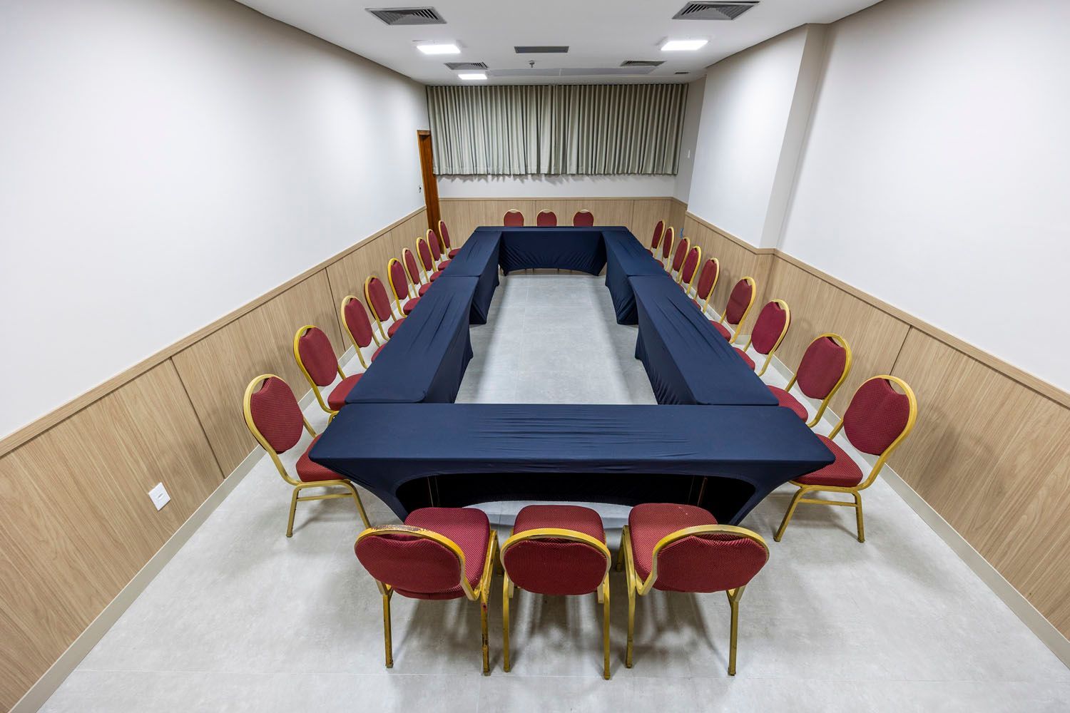 Uma sala de conferências com uma longa mesa em forma de U e cadeiras.