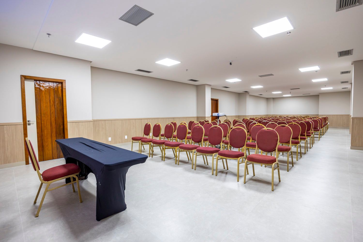 Uma grande sala de conferências com fileiras de cadeiras e uma mesa.