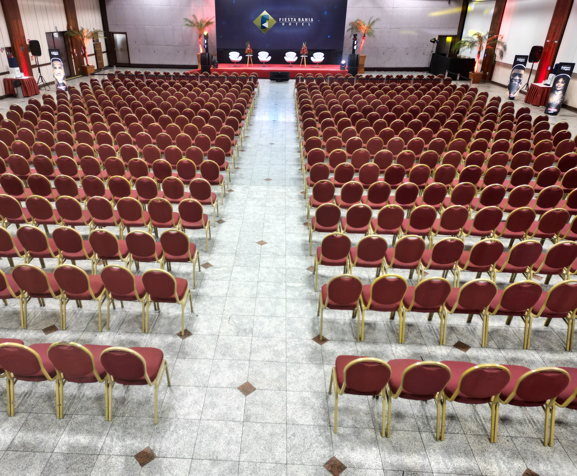 Fileiras de cadeiras vermelhas estão alinhadas em uma grande sala