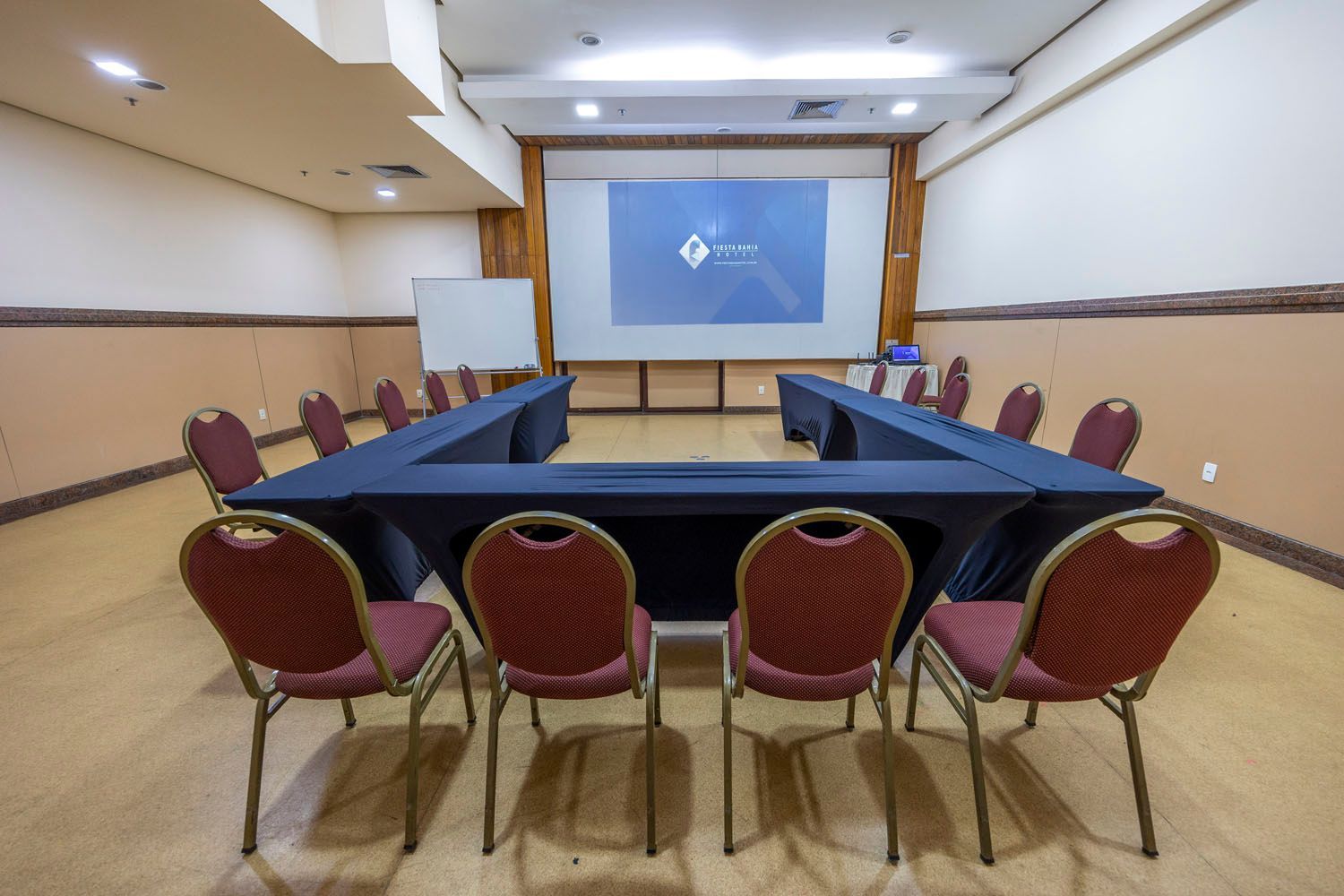 Uma sala de conferências com mesas e cadeiras e uma tela de projetor.