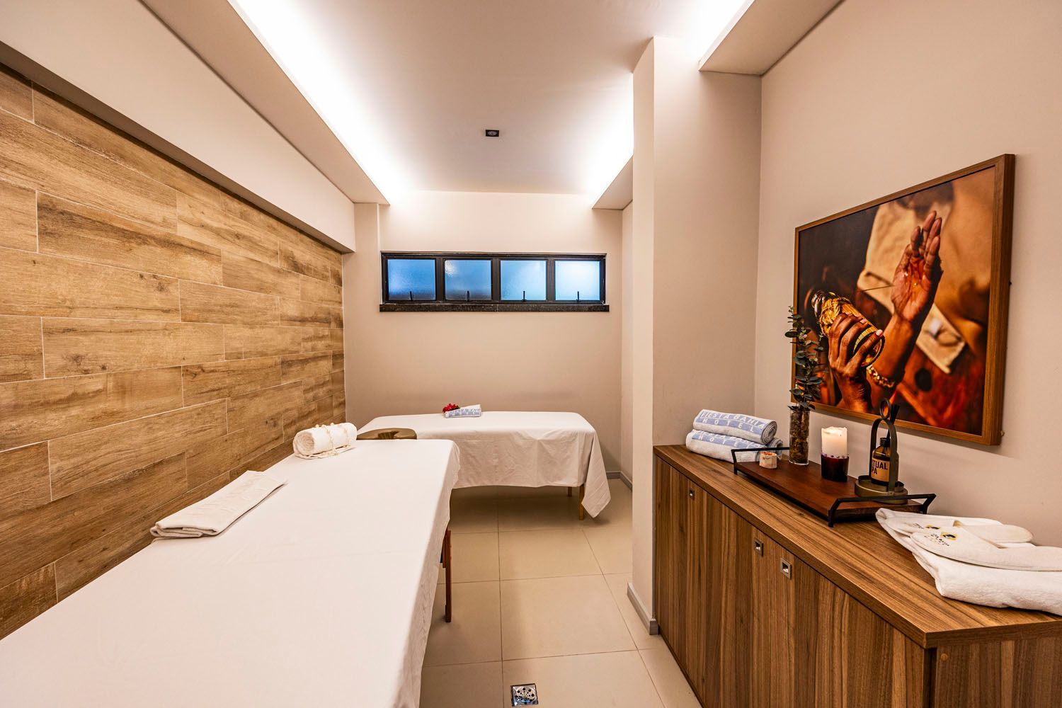 Um quarto com duas camas de massagem e uma pintura na parede.
