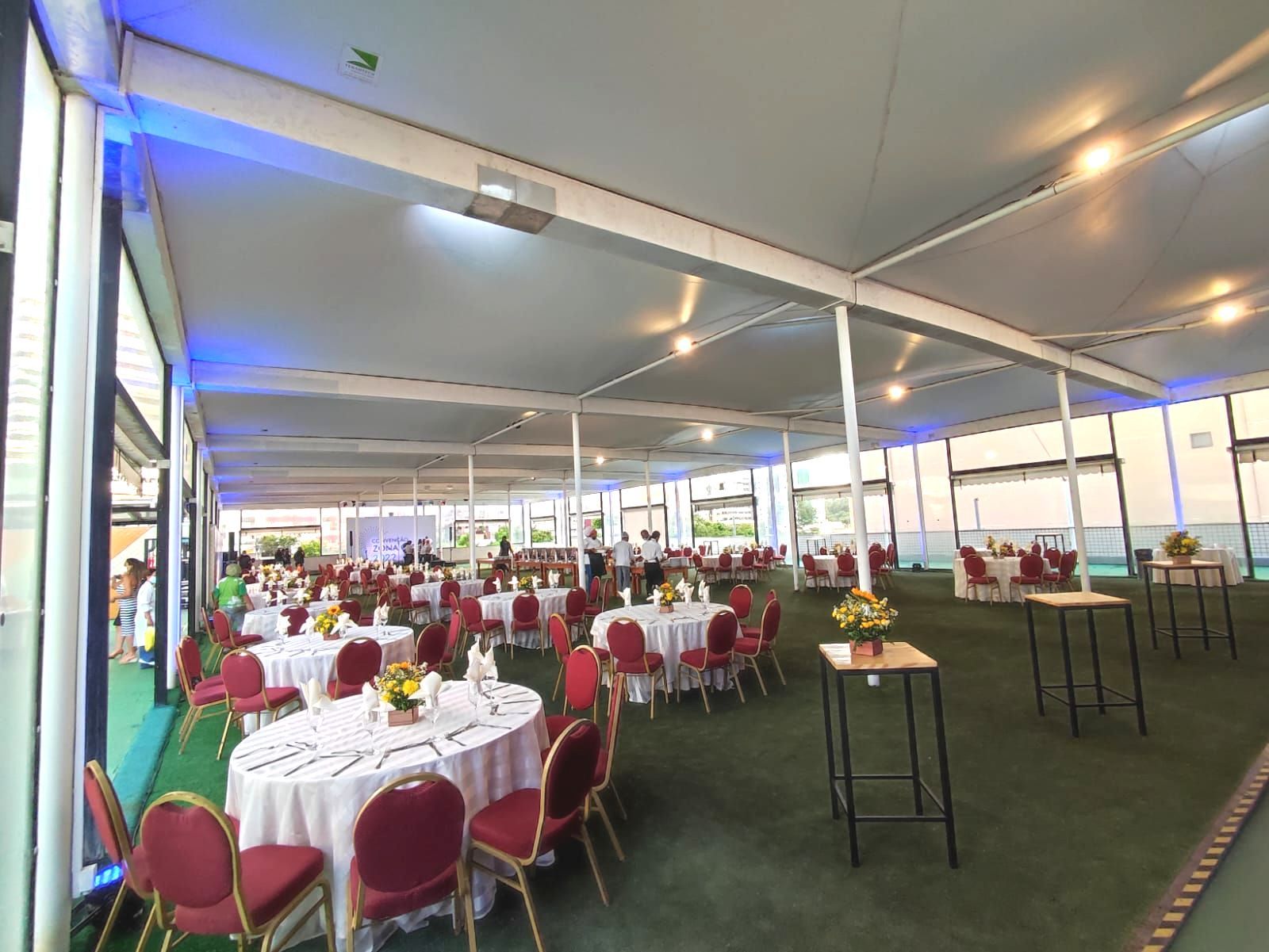 Uma sala grande com mesas e cadeiras preparadas para uma festa