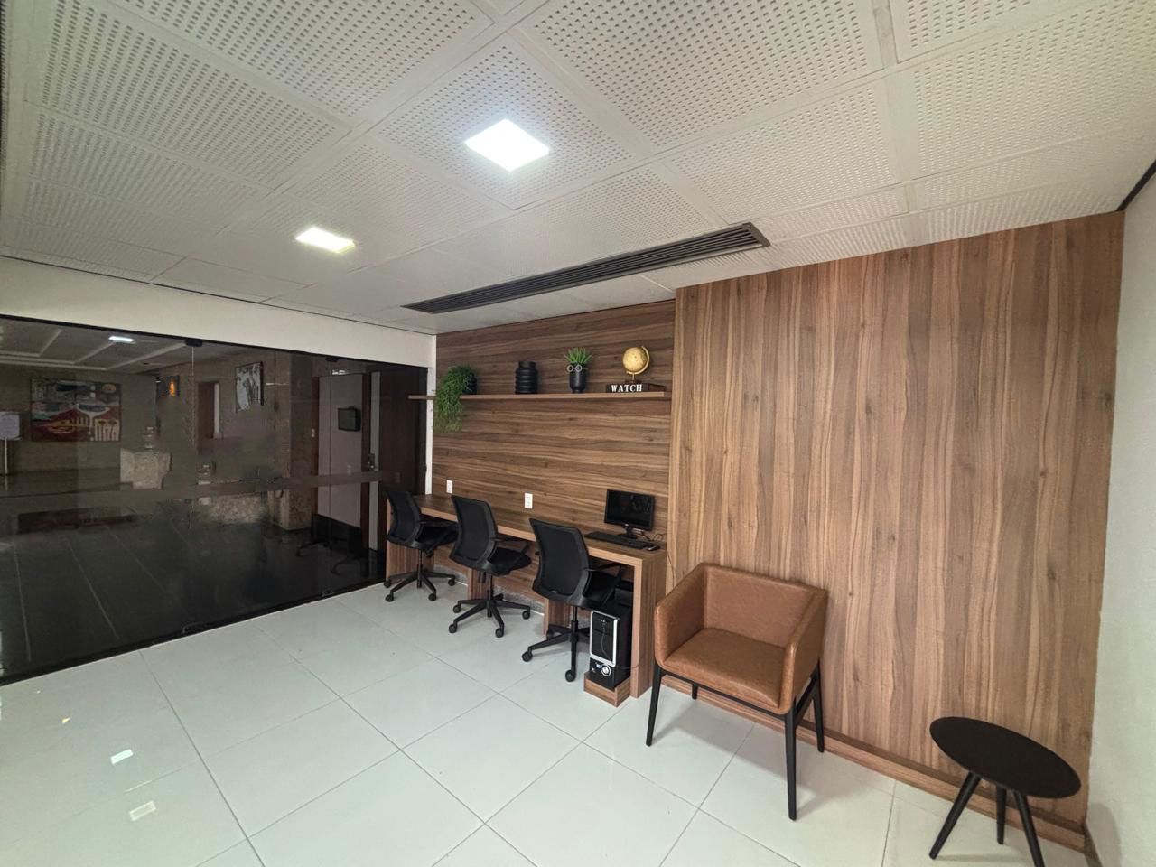 Uma sala com uma fileira de mesas e cadeiras.