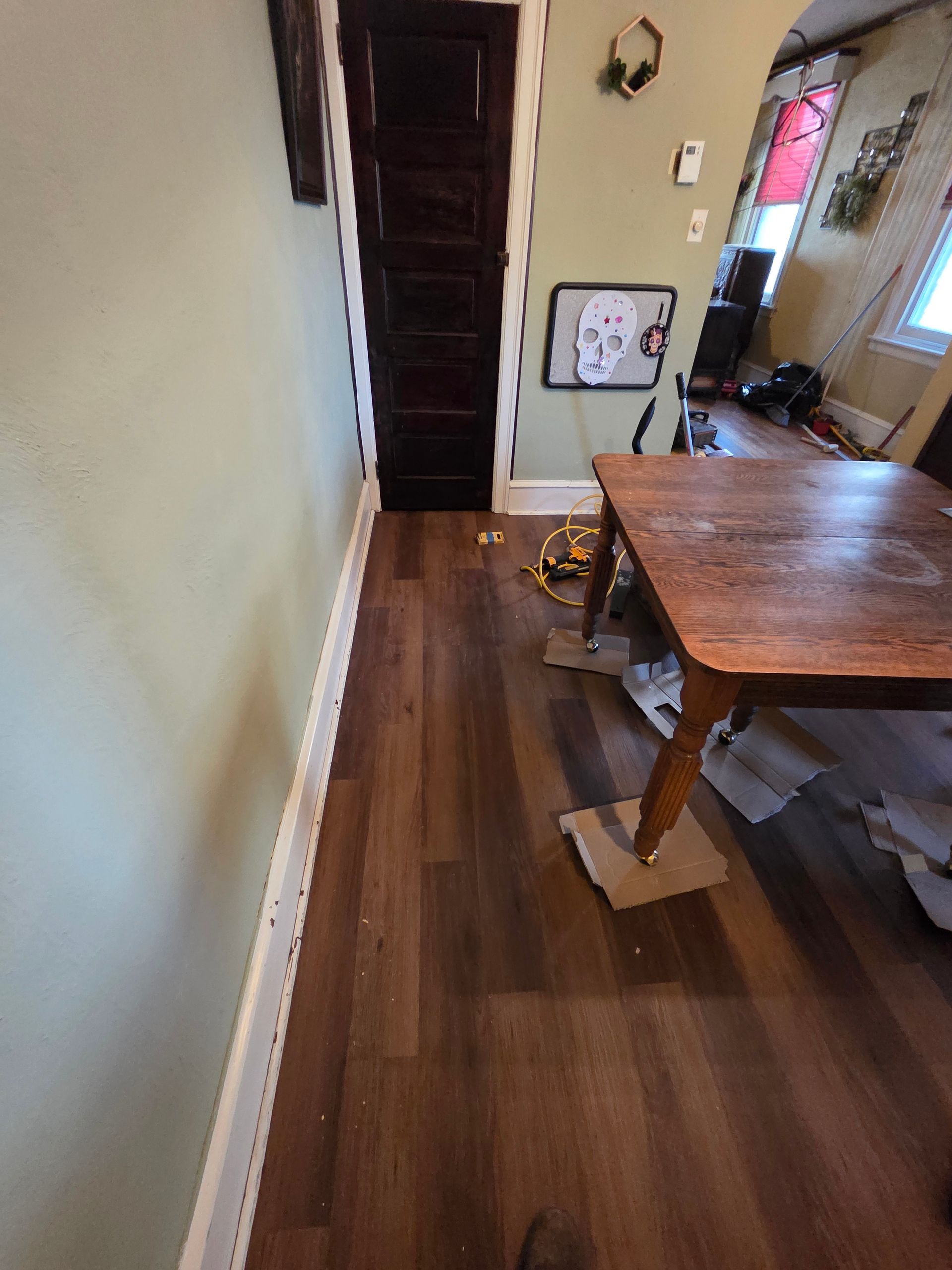 View of a room with hardwood flooring, windows, and a doorway. The view is from above a staircase railing.