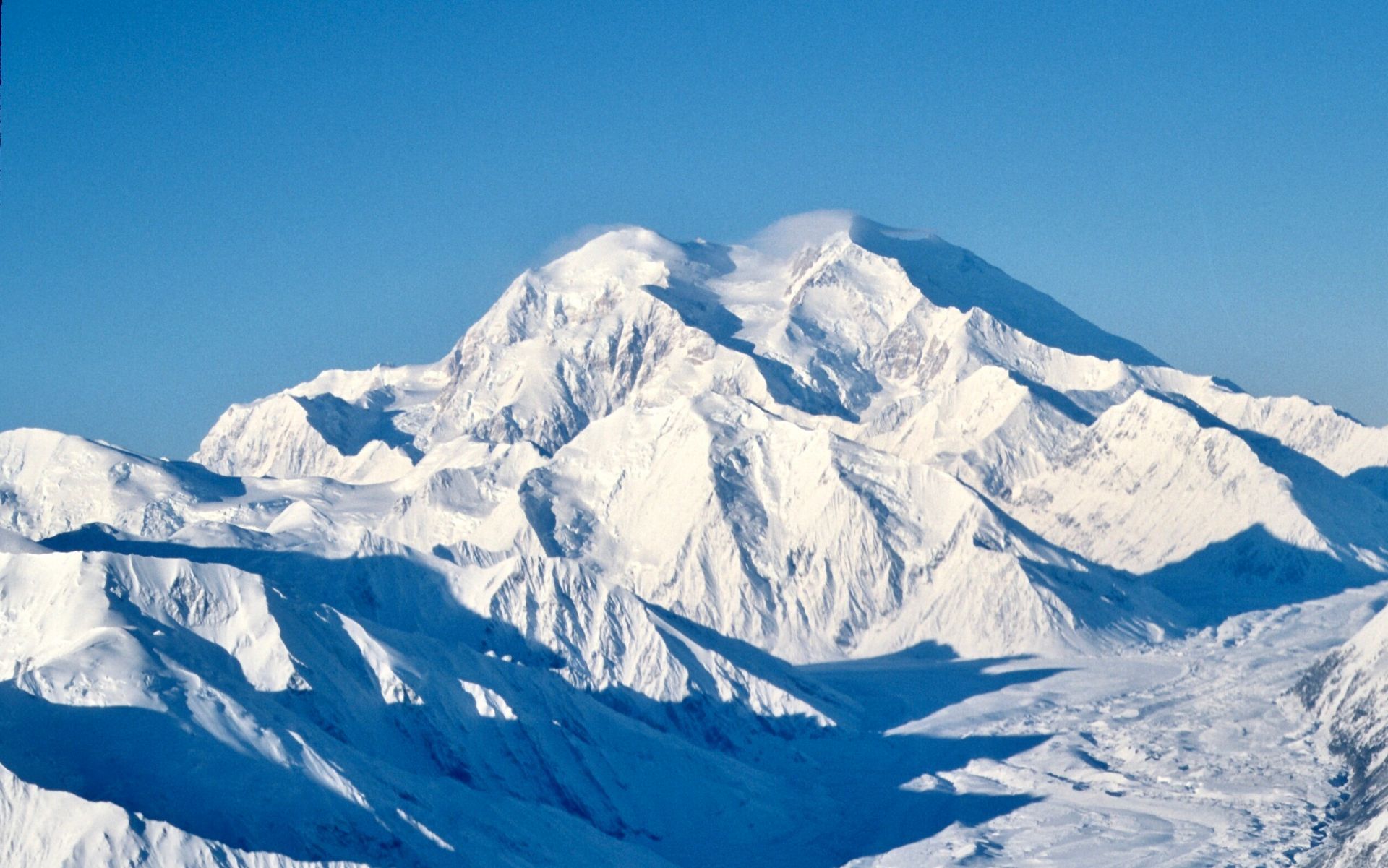 A snowy mountain with a blue sky in the background