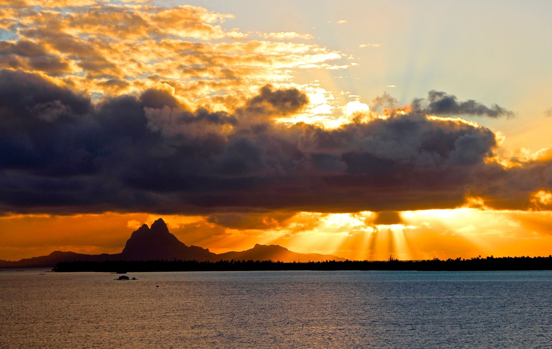 The sun is shining through the clouds over the ocean.