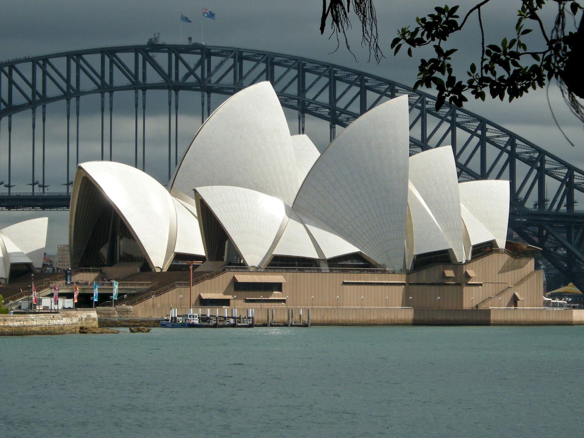 The sydney opera house sits in the middle of a body of water