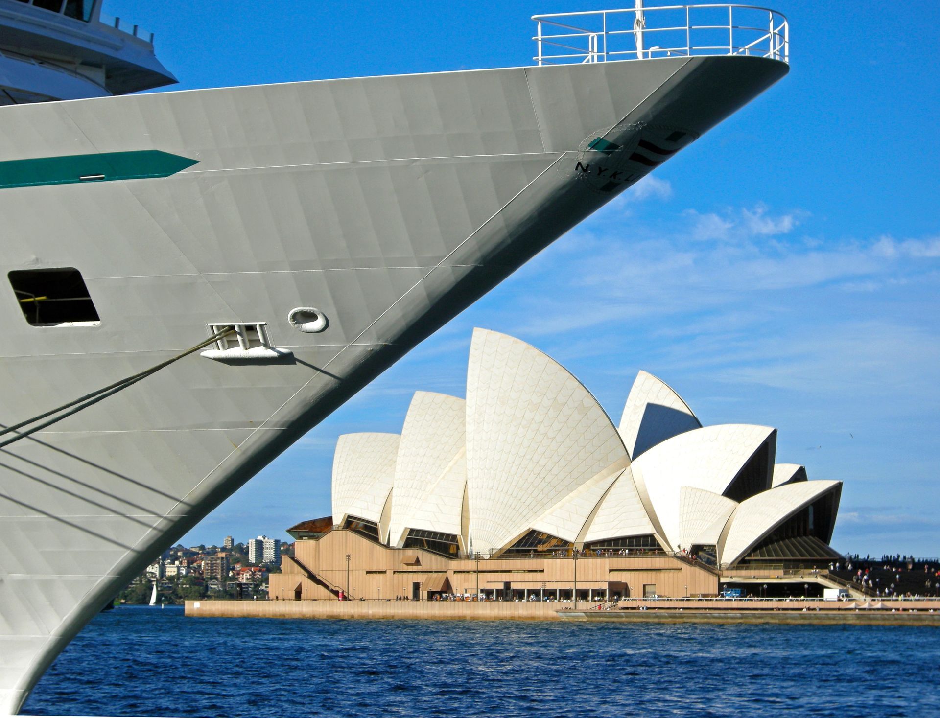 The sydney opera house is visible behind a cruise ship