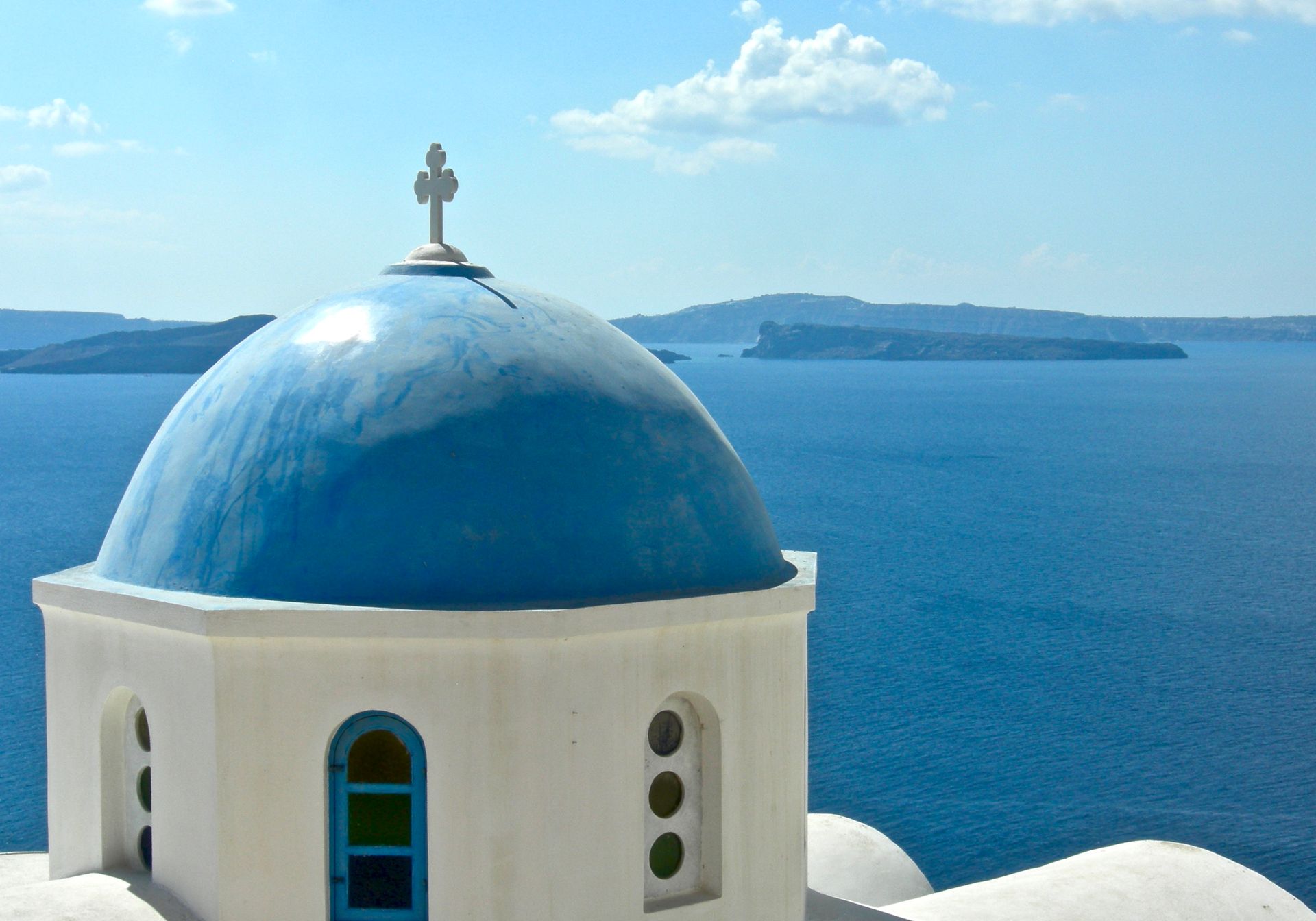 A white building with a blue dome and a cross on top