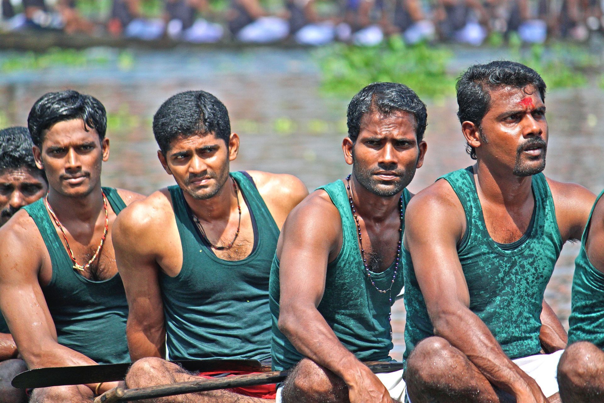 A group of men in green tank tops are sitting in a boat