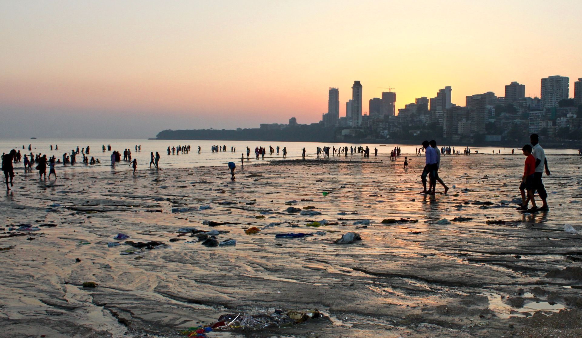 People walking on a beach with a city in the background