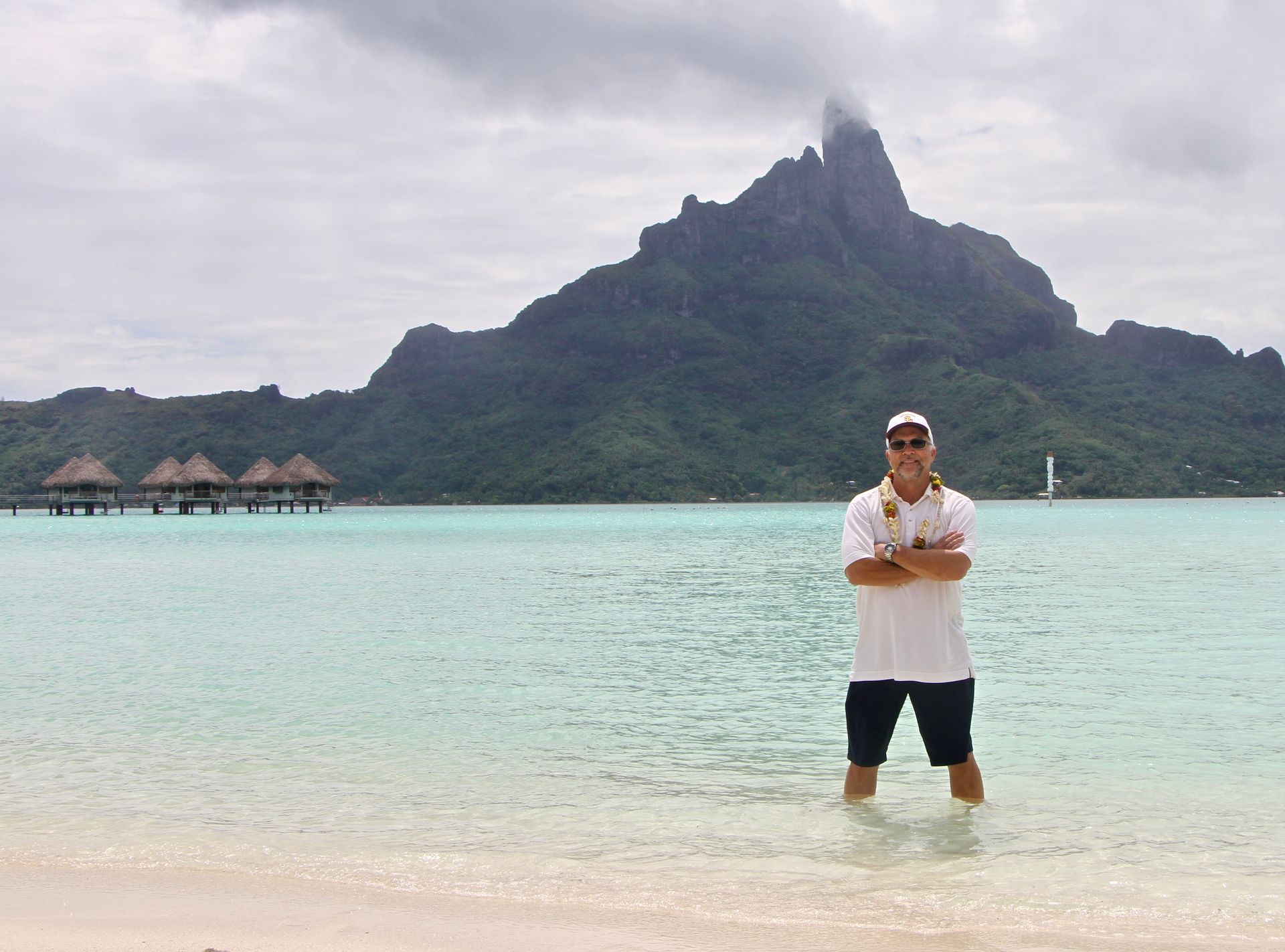 A man standing in the water with a mountain in the background