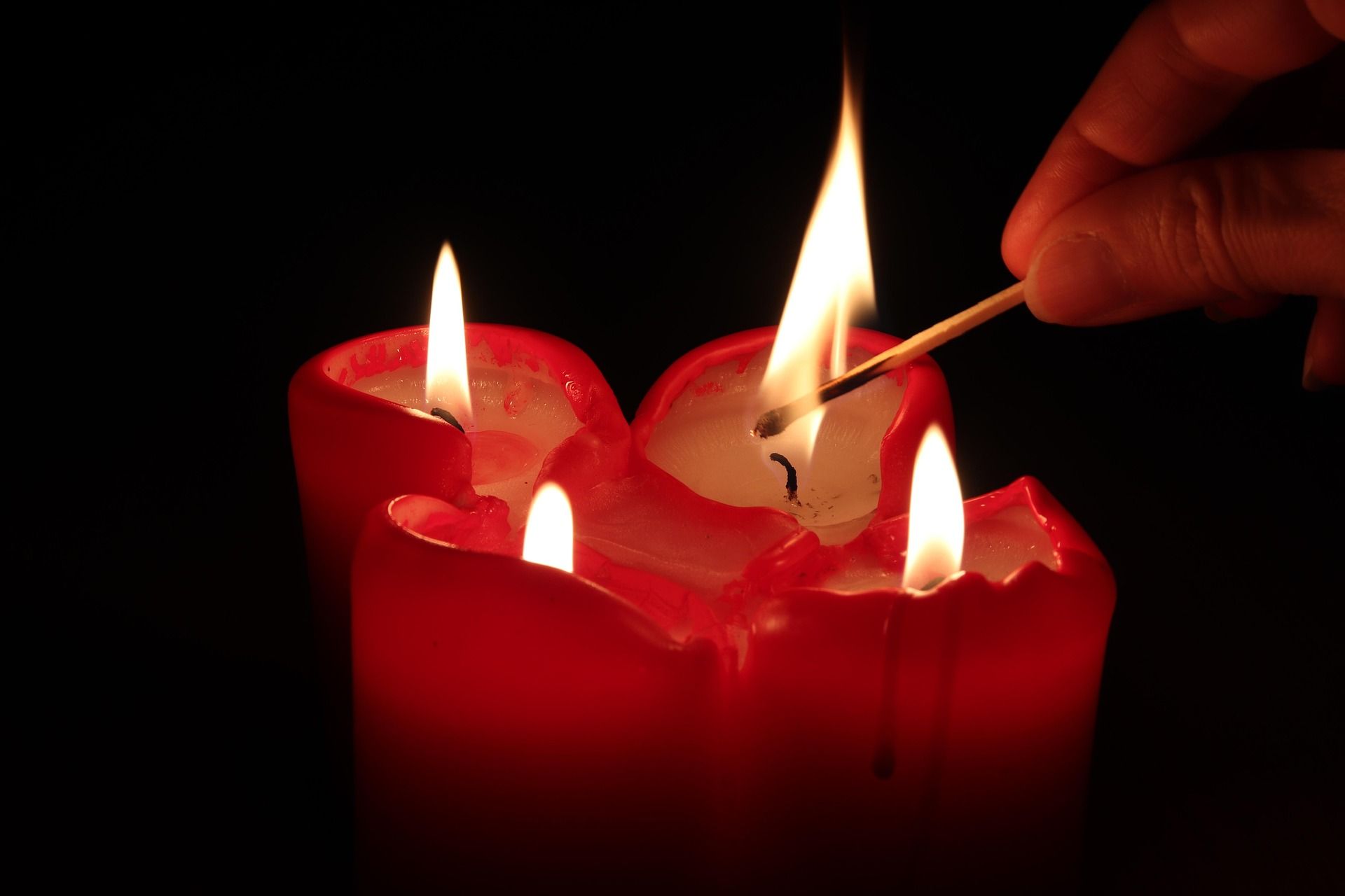 Red candles lit with a match against a black background.