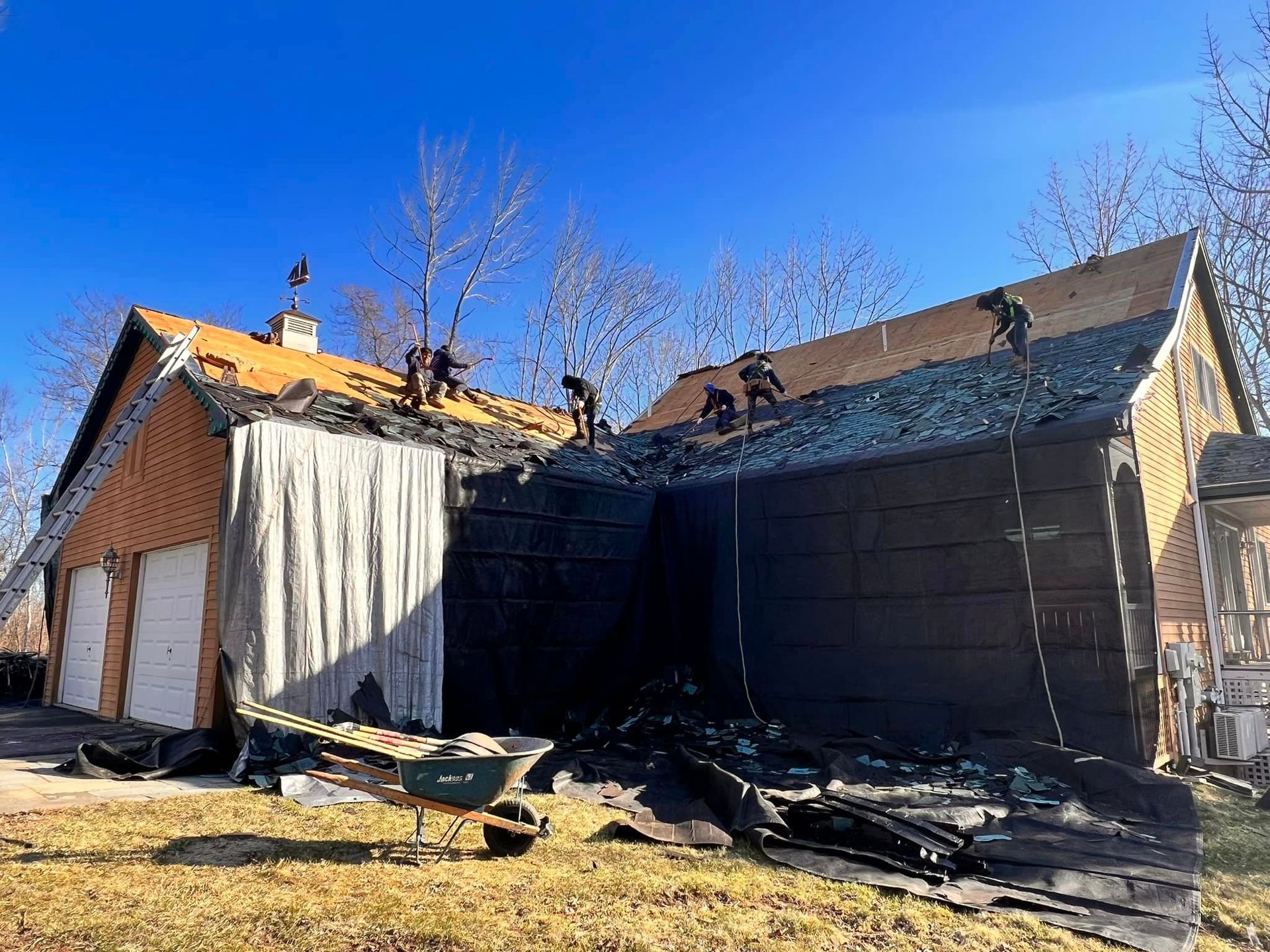 A group of people are working on the roof of a house.