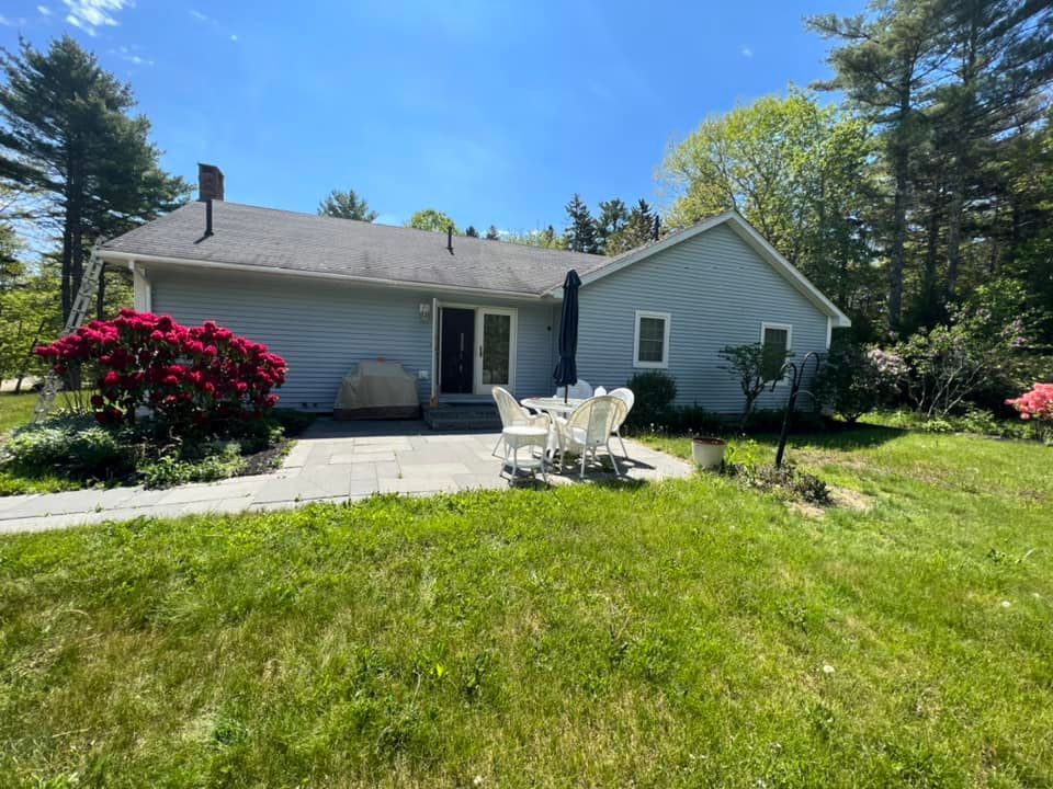 A white house with a patio and chairs in front of it.