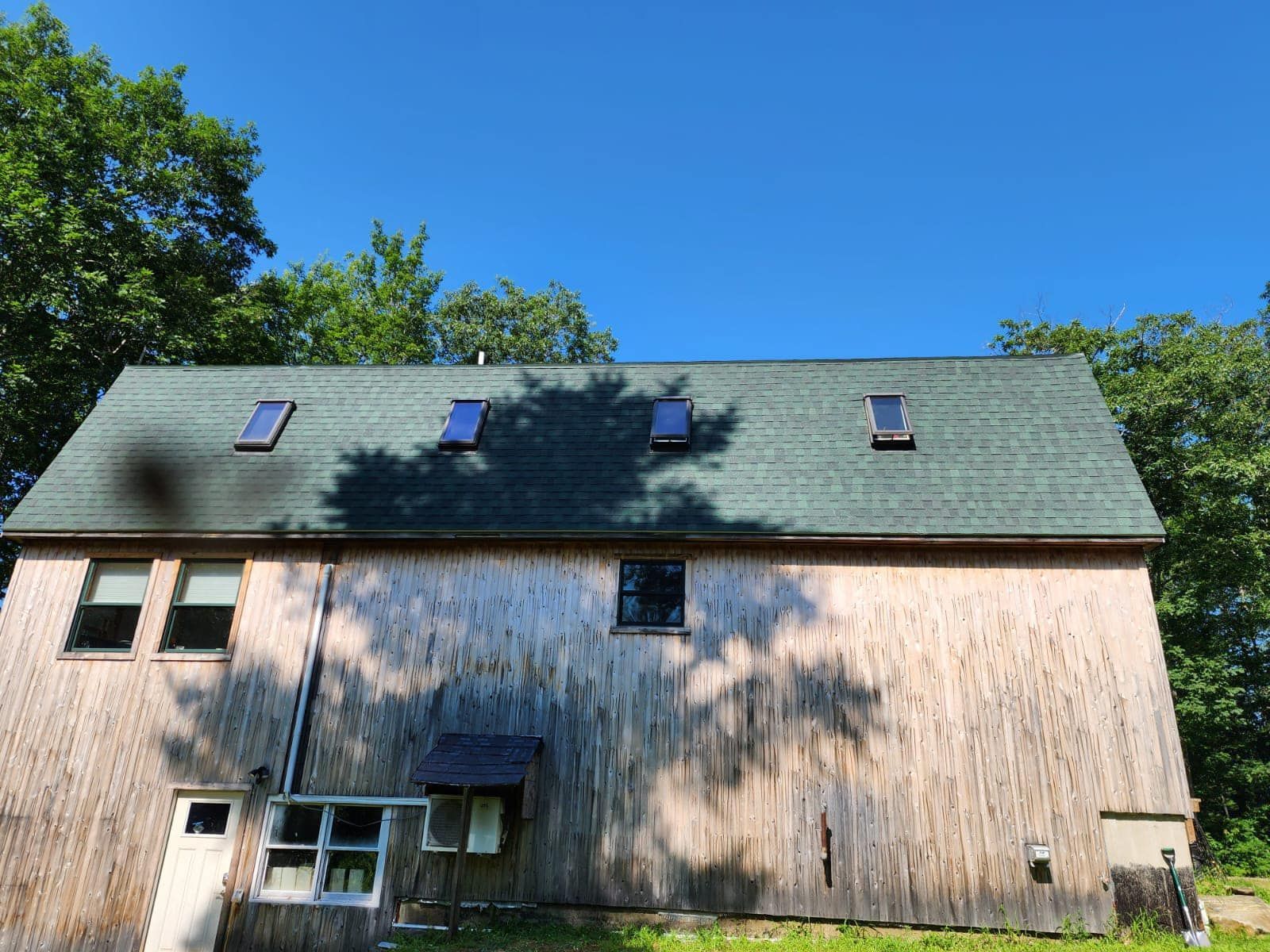 A large wooden house with a green roof and skylights.