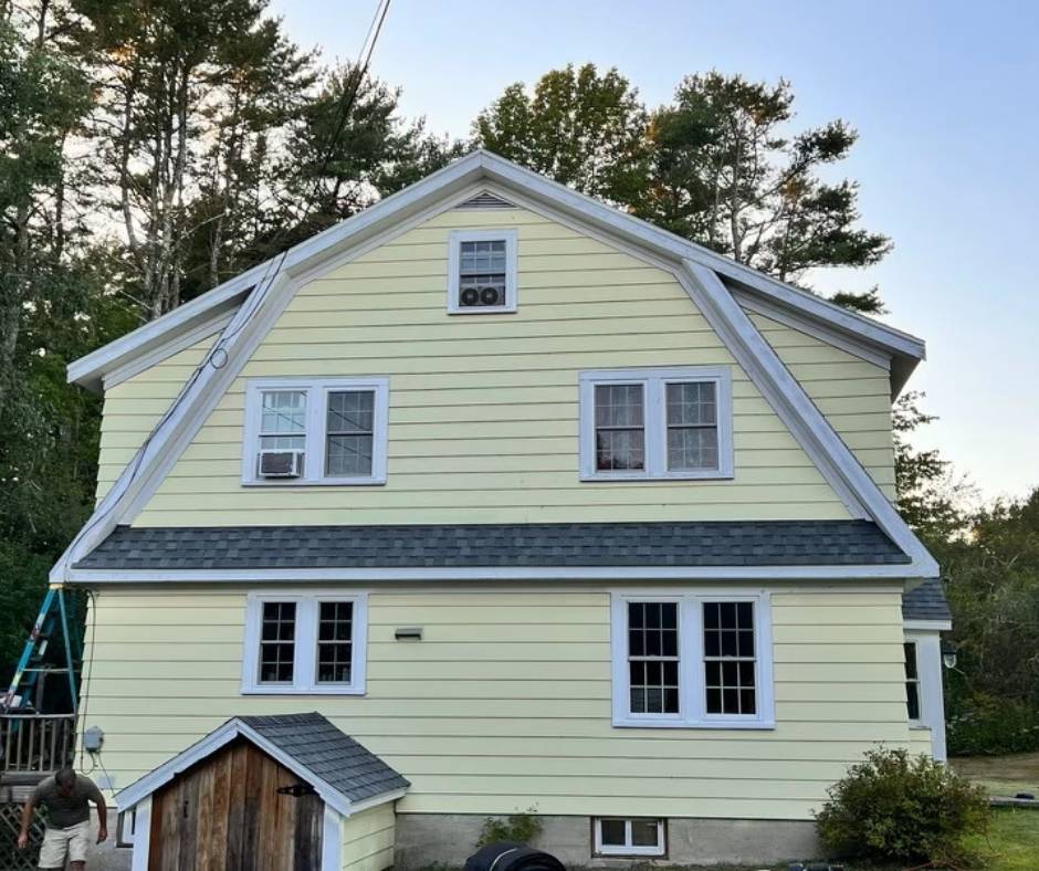 A yellow house with a black roof and white trim