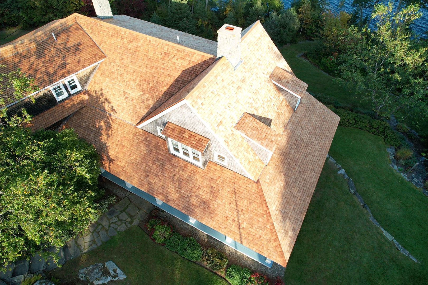 An aerial view of a house with a roof that is surrounded by trees.