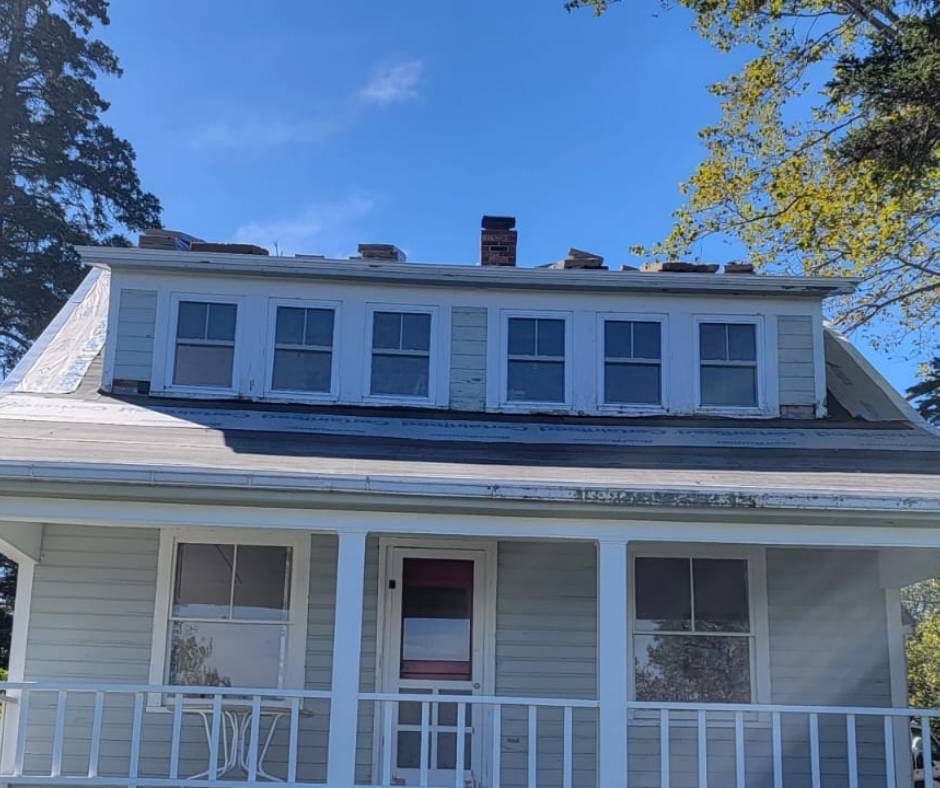 A house with a porch and a chimney on the roof
