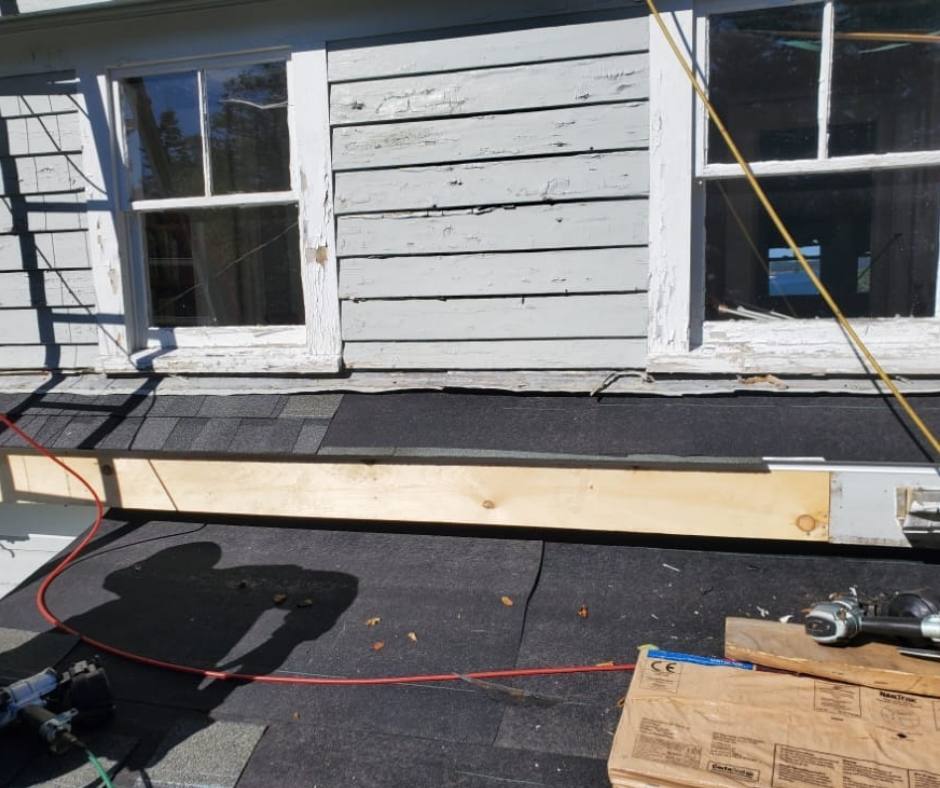 A wooden beam is sitting on the roof of a house