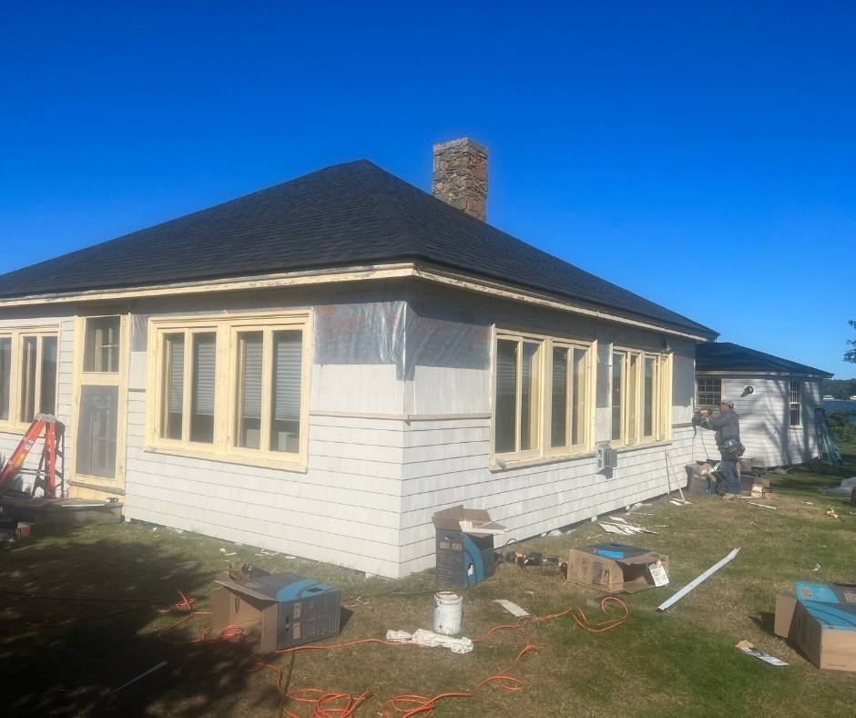 A white house with a black roof is being remodeled.