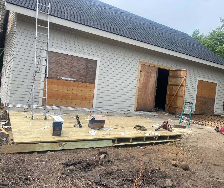 A wooden deck is being built in front of a garage under construction.