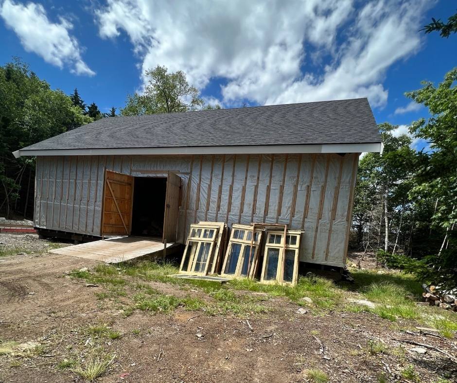 A shed with a lot of windows sitting in front of it.