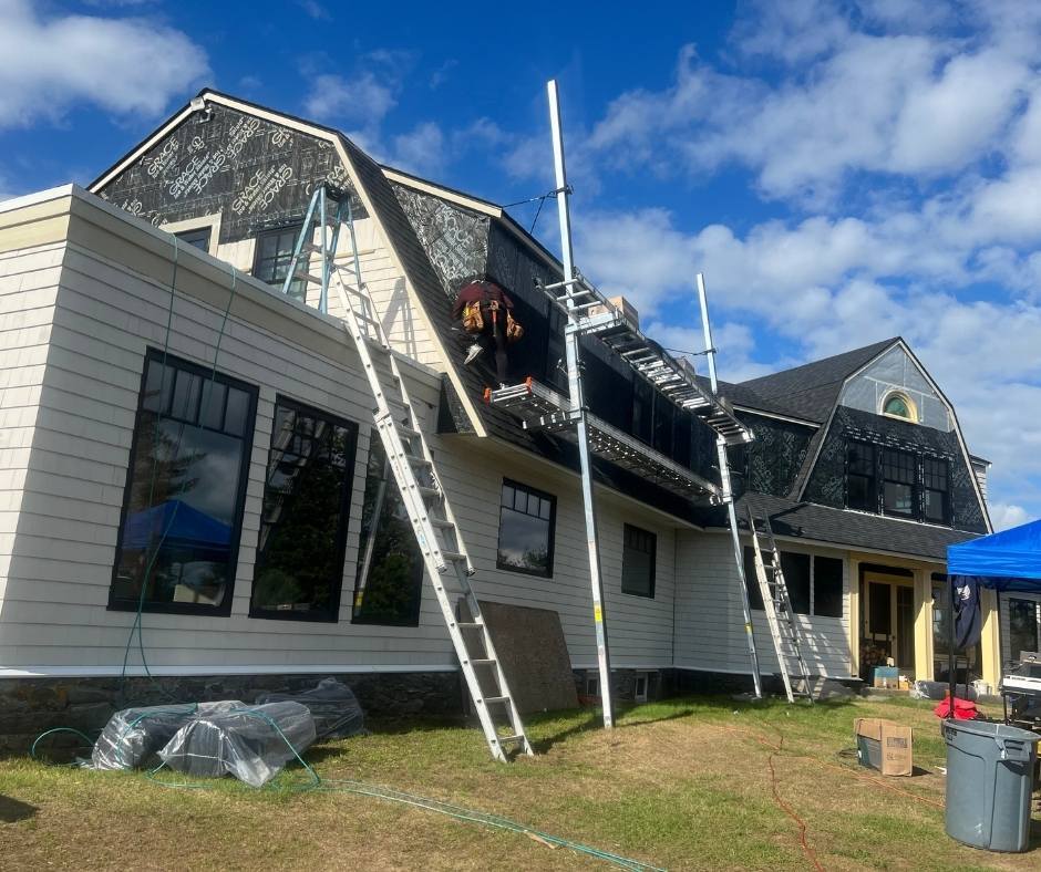 A man is standing on a ladder on the side of a house.