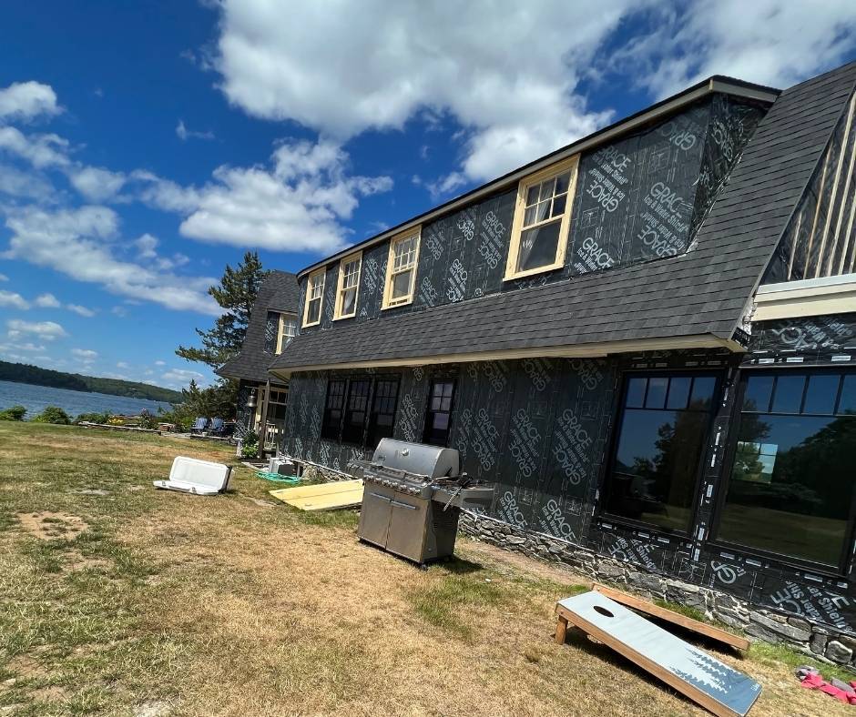 A large house is being built with a lot of windows and a grill in the backyard.