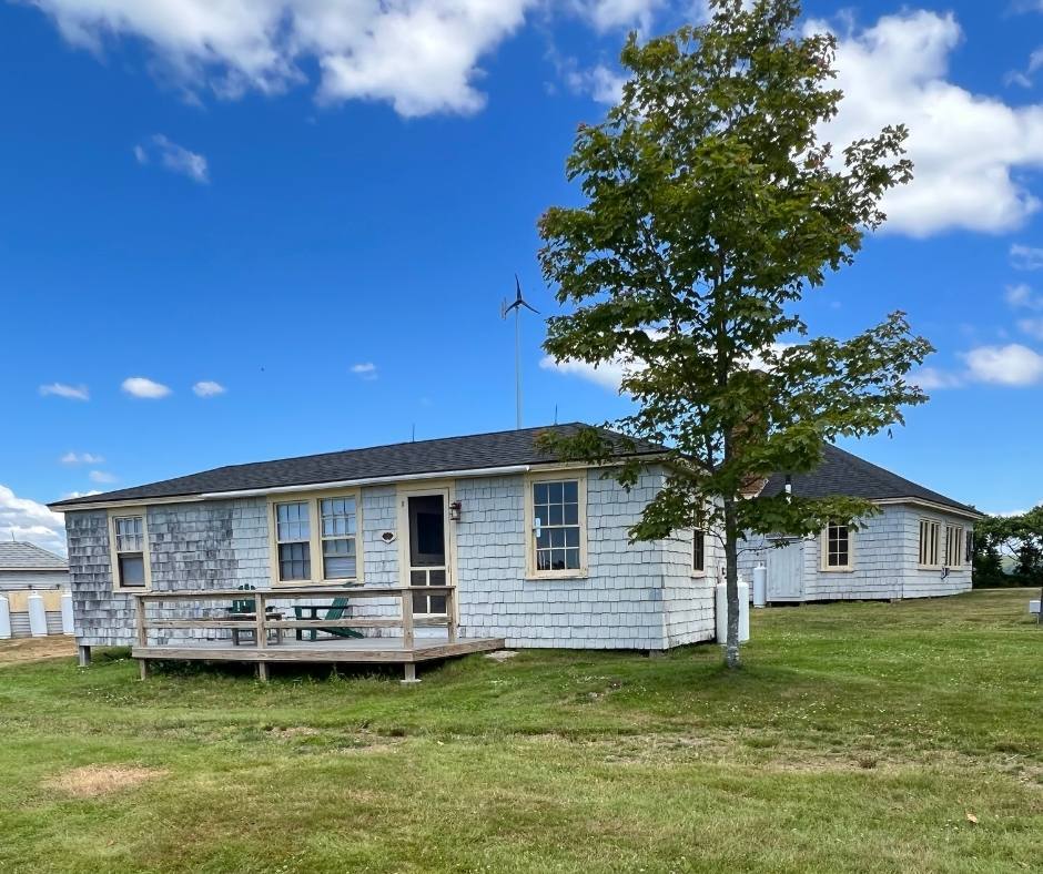 A white house with a deck and a tree in front of it