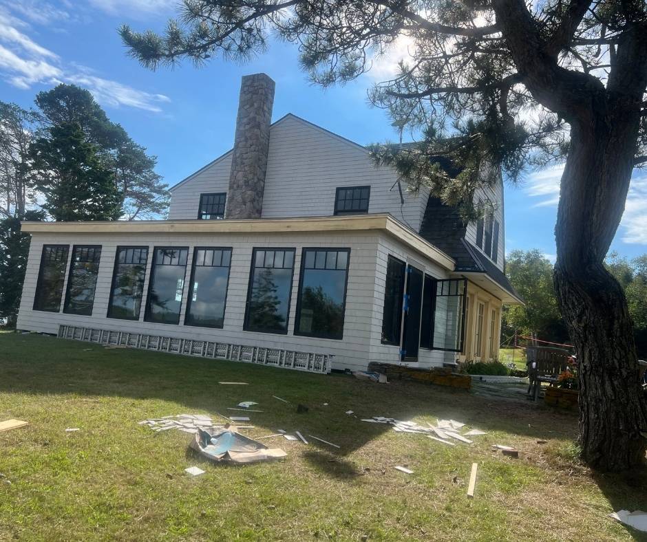 A large white house with a lot of windows is sitting on top of a lush green field.