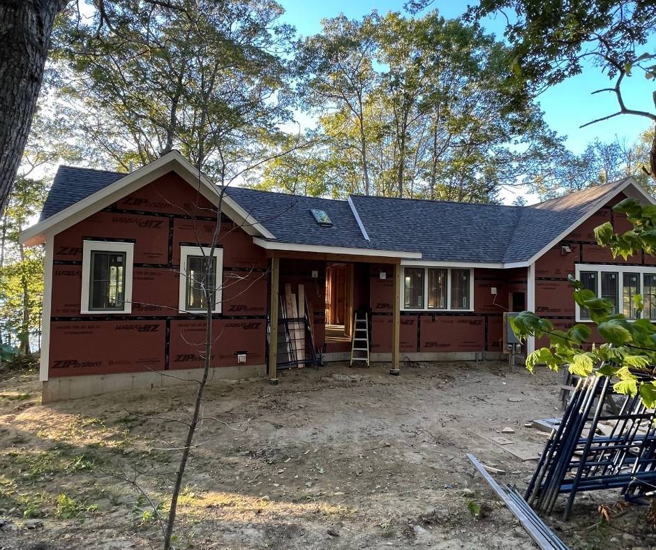 A red house with a blue roof is being built in the woods.